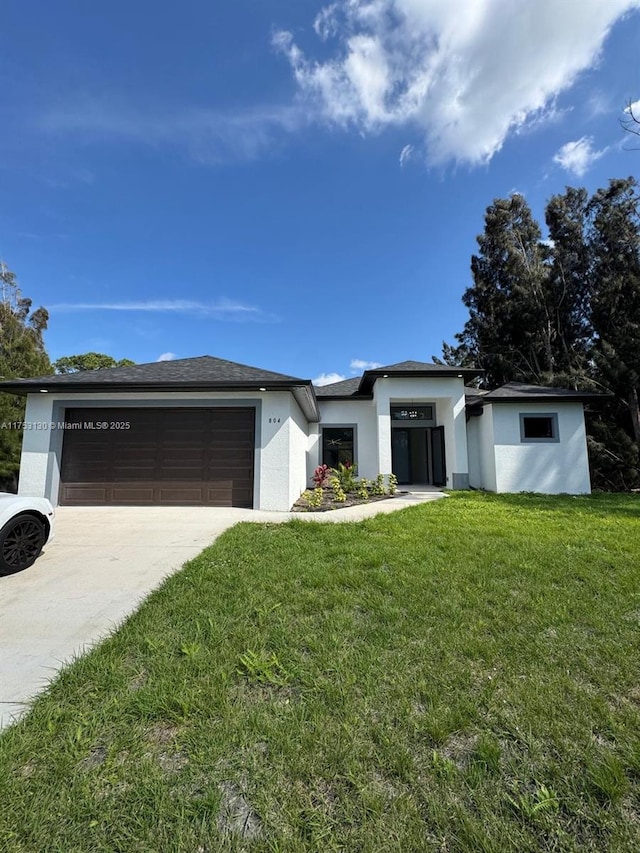 prairie-style house featuring a garage, a front yard, concrete driveway, and stucco siding