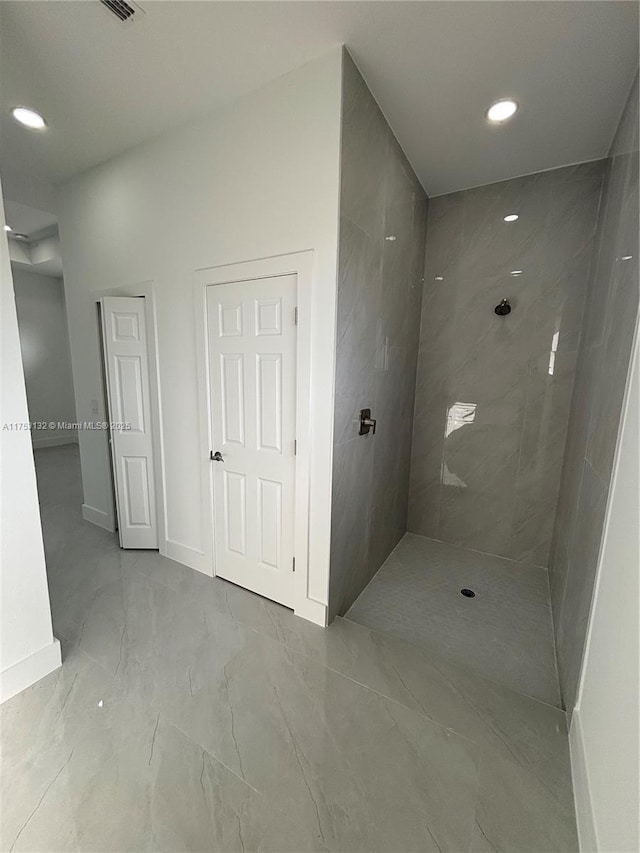 bathroom with recessed lighting, marble finish floor, tiled shower, and baseboards