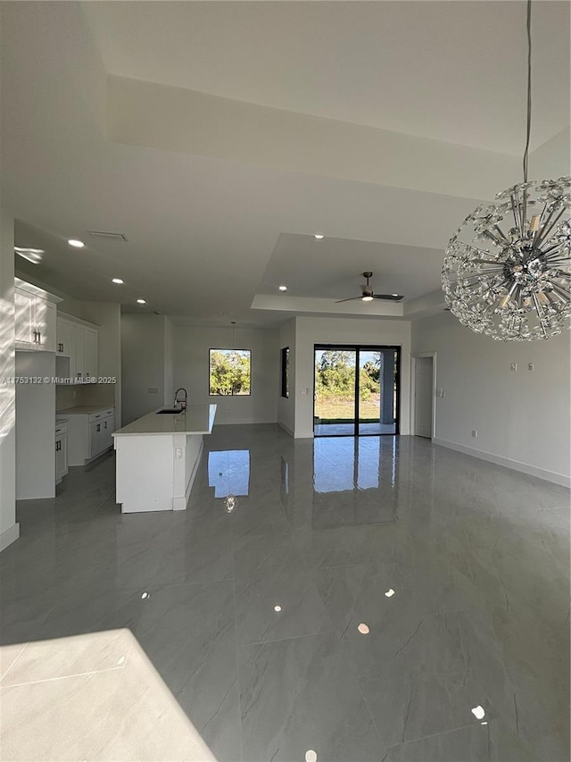 unfurnished living room with marble finish floor, ceiling fan, and baseboards