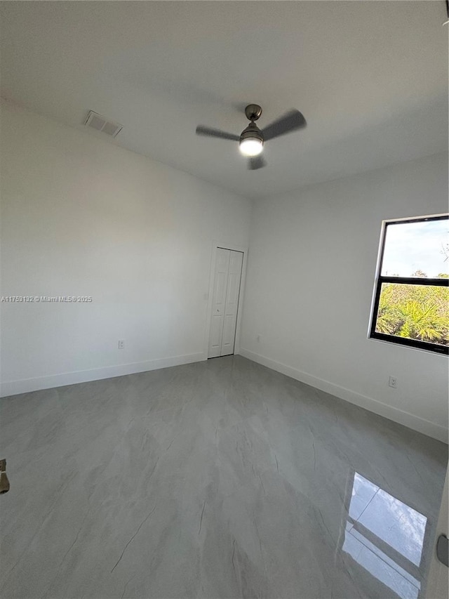 spare room with a ceiling fan, visible vents, and baseboards