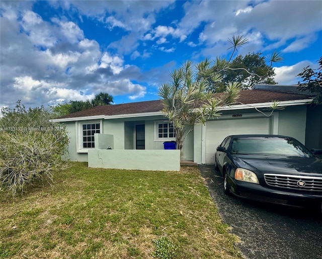 view of front of property with a garage, driveway, a front lawn, and stucco siding