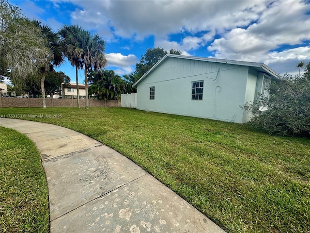 view of side of home with fence and a yard