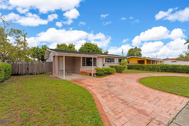 back of house featuring stucco siding, fence, decorative driveway, and a yard