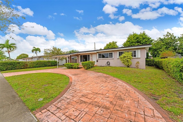 ranch-style house with brick siding, decorative driveway, and a front yard