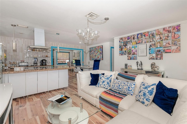 living room featuring a toaster, visible vents, a notable chandelier, and light wood finished floors