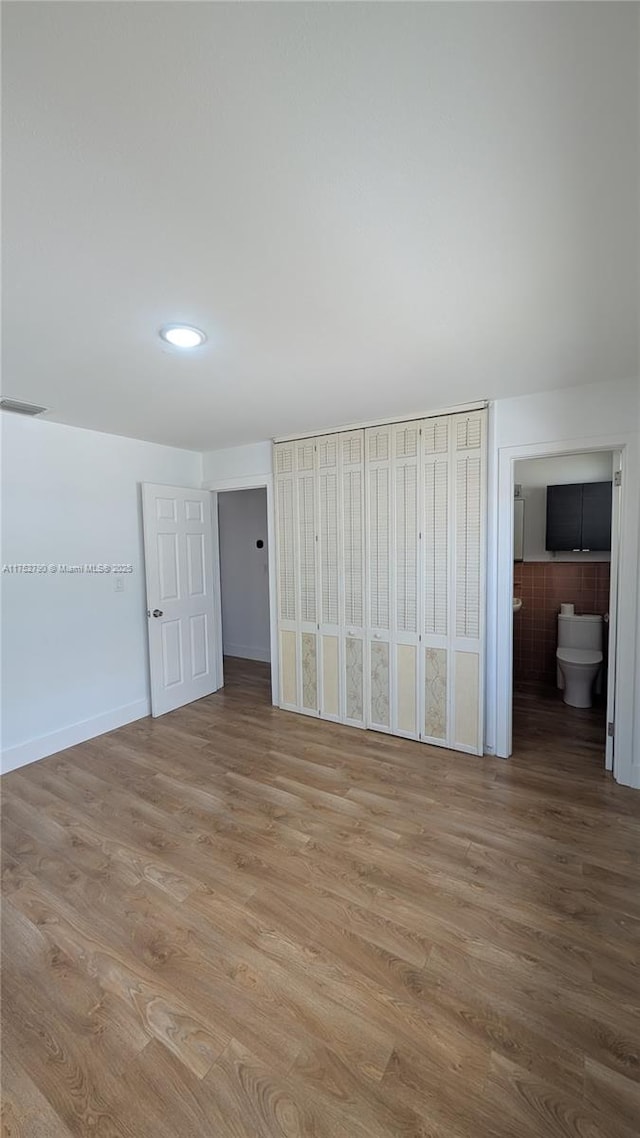 unfurnished bedroom with recessed lighting, ensuite bathroom, light wood finished floors, and visible vents