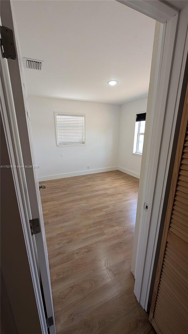 corridor with baseboards, recessed lighting, wood finished floors, and visible vents