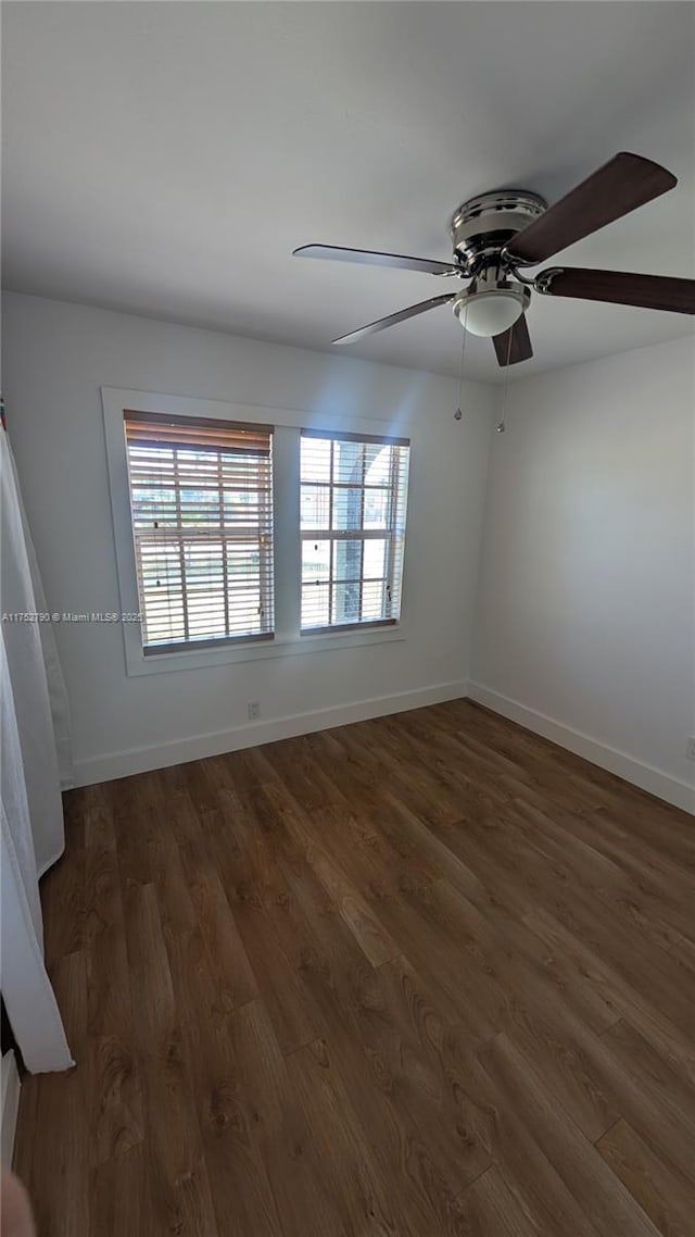 unfurnished room featuring baseboards, ceiling fan, and dark wood-style flooring