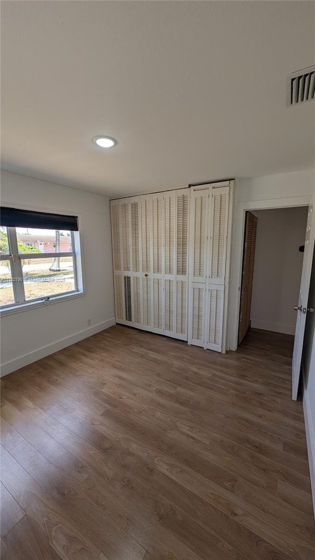unfurnished bedroom featuring recessed lighting, baseboards, dark wood-style flooring, and visible vents
