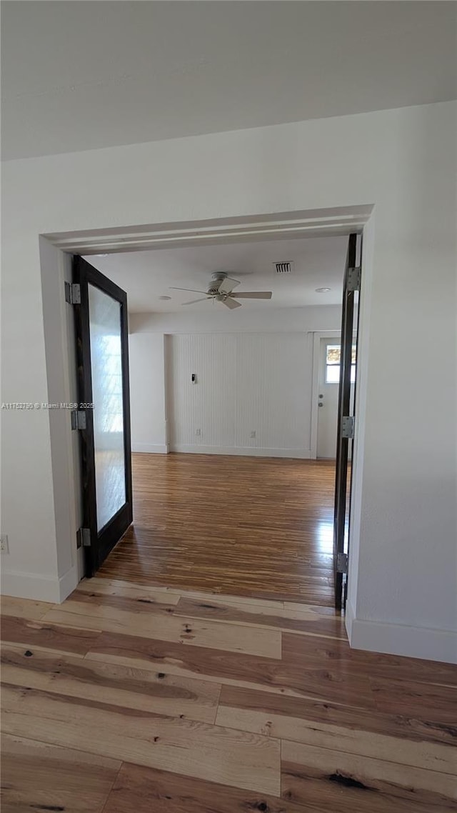 hallway featuring baseboards, visible vents, and light wood-type flooring