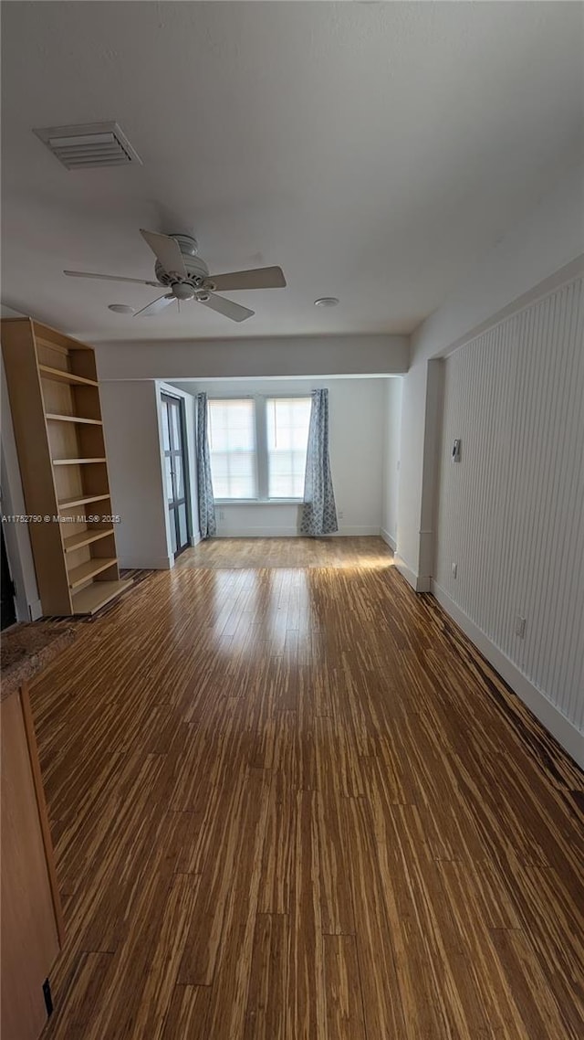 unfurnished living room featuring baseboards, a ceiling fan, wood finished floors, and visible vents