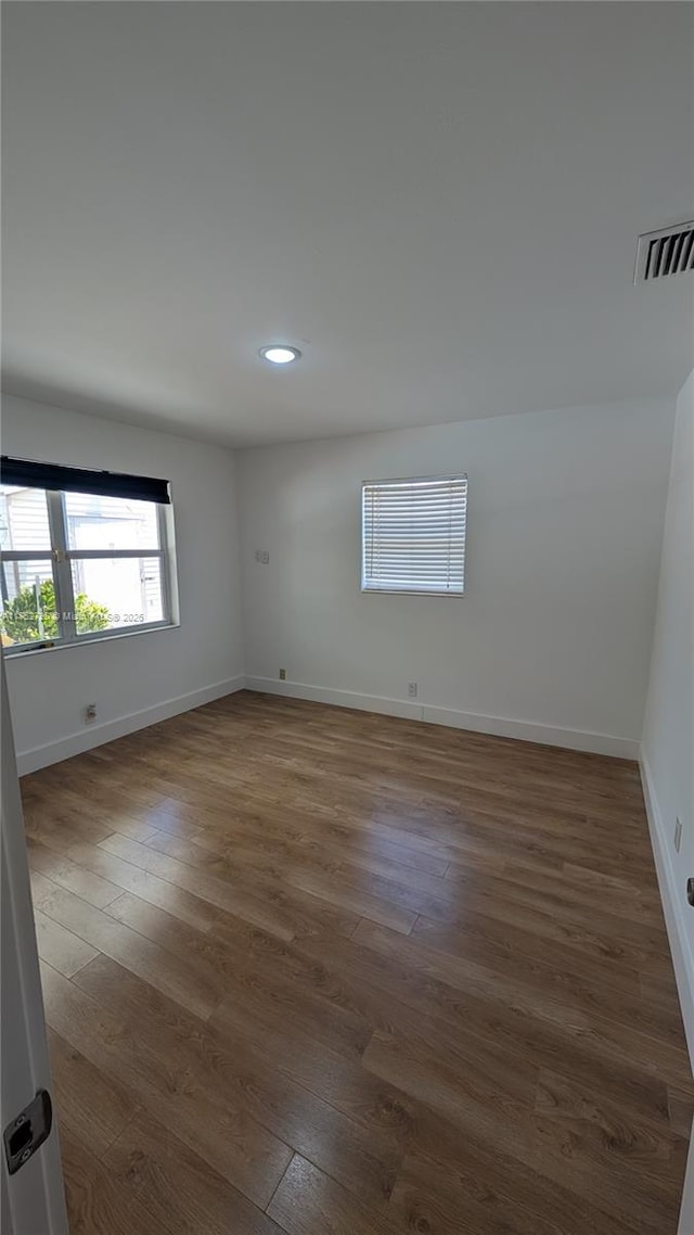 spare room with dark wood-style flooring, baseboards, visible vents, and recessed lighting