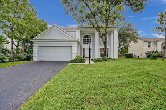 neoclassical / greek revival house featuring an attached garage, stucco siding, driveway, and a front yard