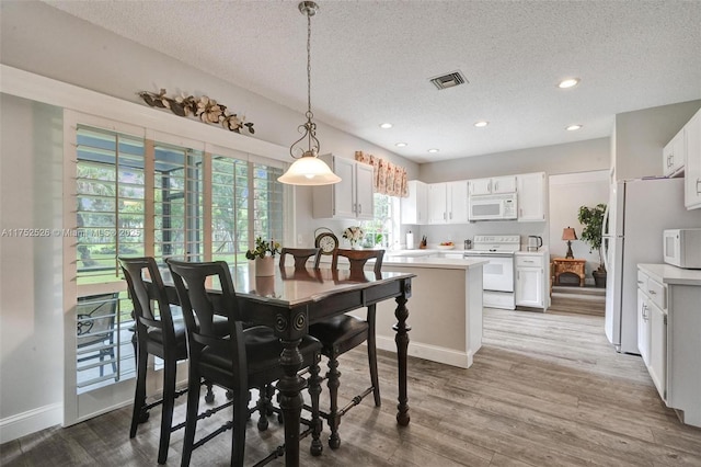 dining room featuring baseboards, visible vents, wood finished floors, a textured ceiling, and recessed lighting