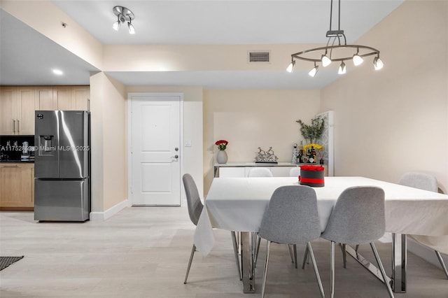 dining area with baseboards, visible vents, and light wood-style floors