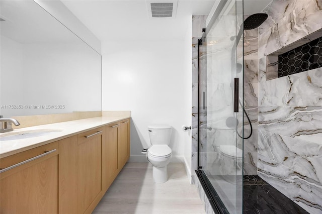 bathroom featuring a marble finish shower, visible vents, vanity, and toilet