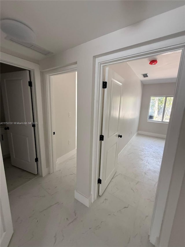 corridor featuring marble finish floor, visible vents, and baseboards