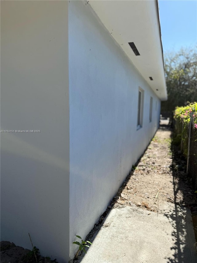 view of side of home with fence and stucco siding