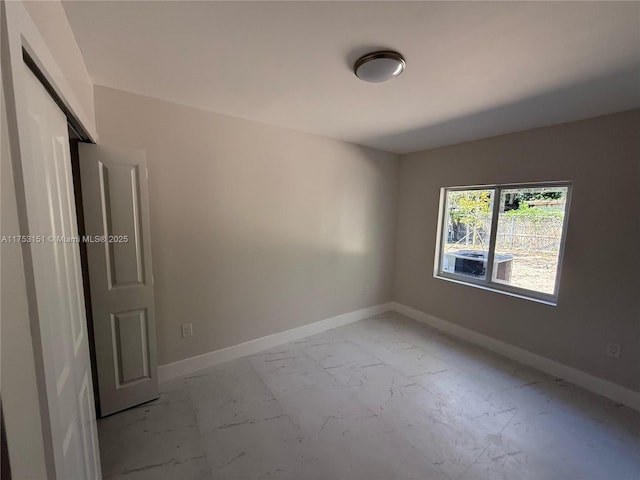 unfurnished room featuring marble finish floor and baseboards