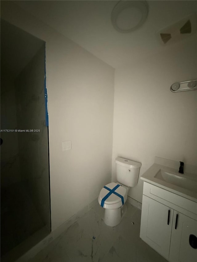 bathroom featuring marble finish floor, vanity, toilet, and walk in shower