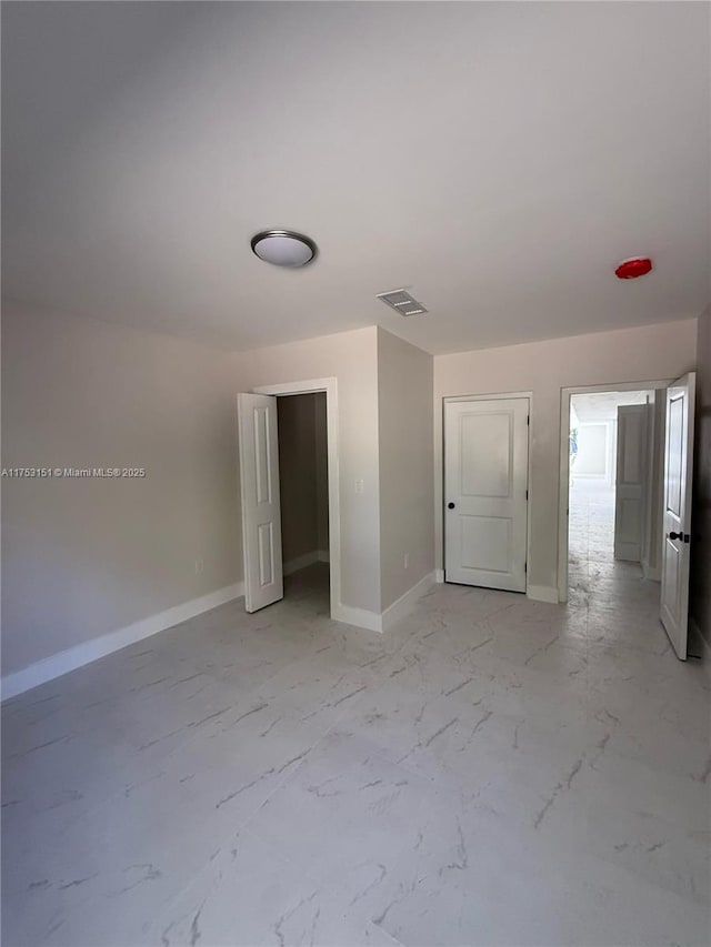 unfurnished bedroom featuring marble finish floor, visible vents, and baseboards