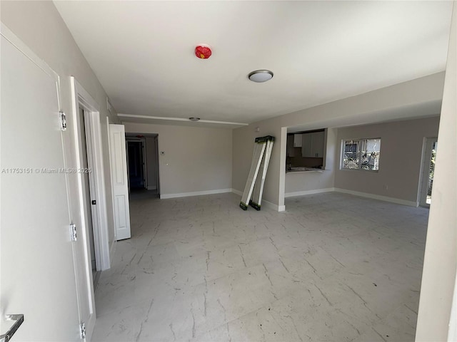 spare room featuring marble finish floor and baseboards