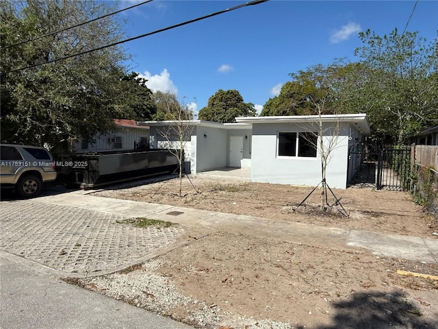 single story home with stucco siding, driveway, and fence