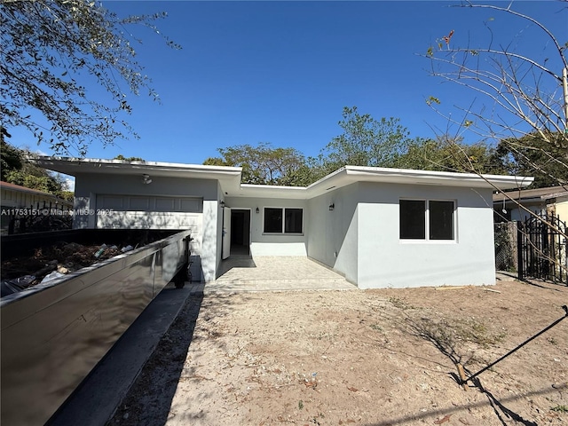 view of front of house with an attached garage, fence, and stucco siding