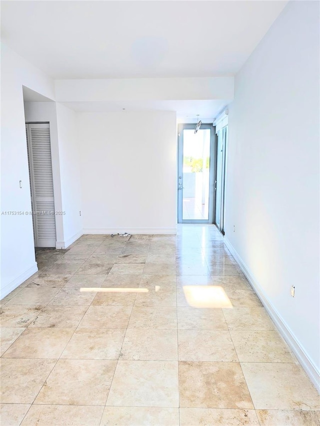 unfurnished room with tile patterned flooring, expansive windows, and baseboards