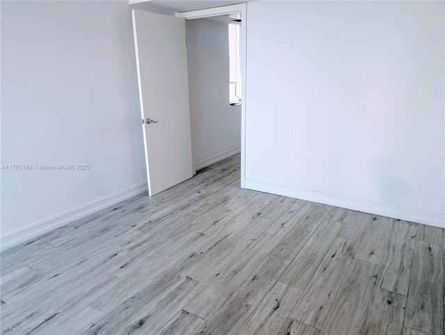 spare room featuring light wood finished floors and baseboards