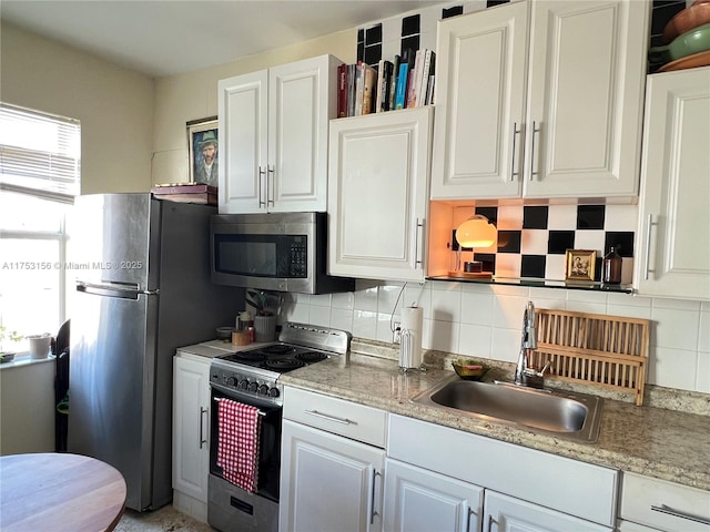 kitchen with stainless steel appliances, white cabinetry, a sink, and decorative backsplash