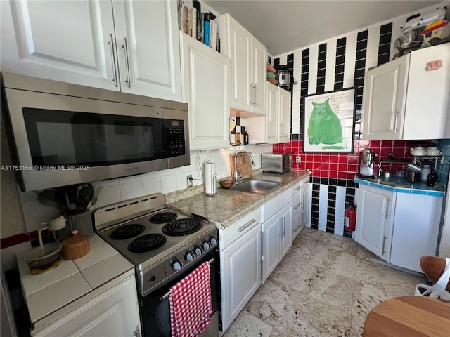 kitchen featuring tile counters, stainless steel microwave, white cabinetry, a sink, and range with electric cooktop