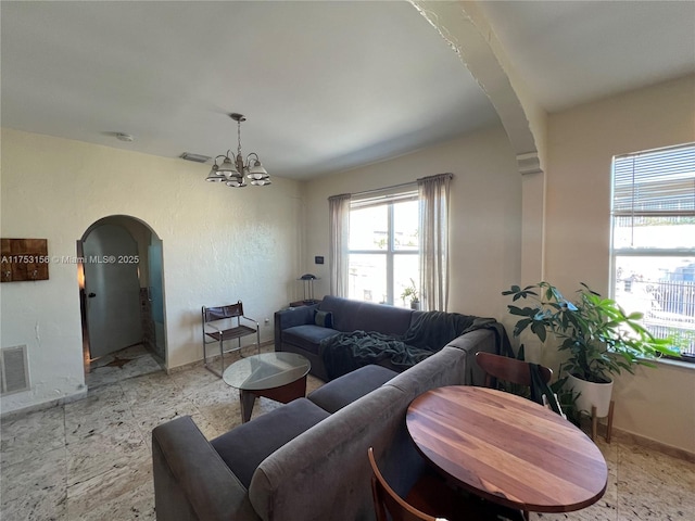 living area with arched walkways, a notable chandelier, visible vents, and baseboards