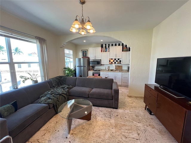 living area featuring arched walkways and a notable chandelier