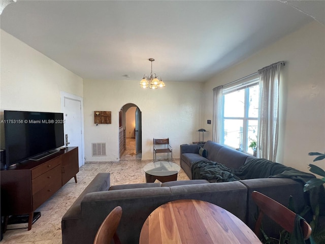 living area with visible vents, arched walkways, a notable chandelier, and light speckled floor