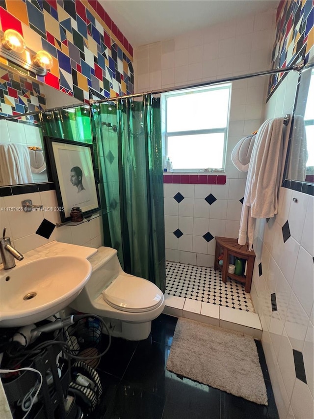 bathroom with a shower stall, tile walls, a sink, and tile patterned floors