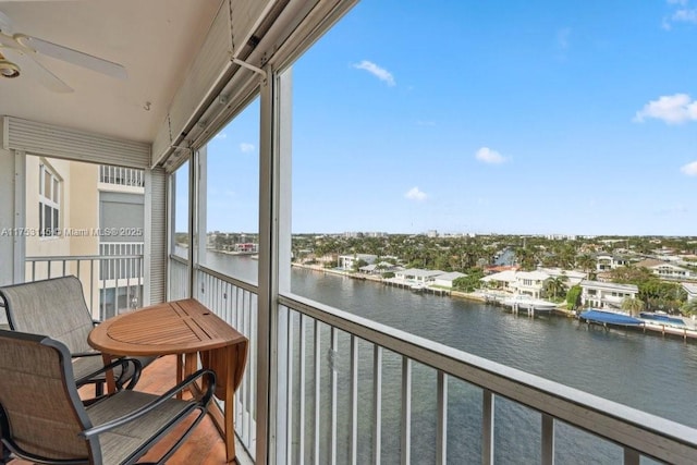 balcony with a sunroom, ceiling fan, and a water view