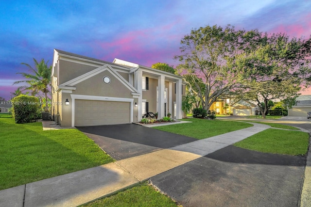 view of front facade featuring a garage, aphalt driveway, a lawn, and stucco siding