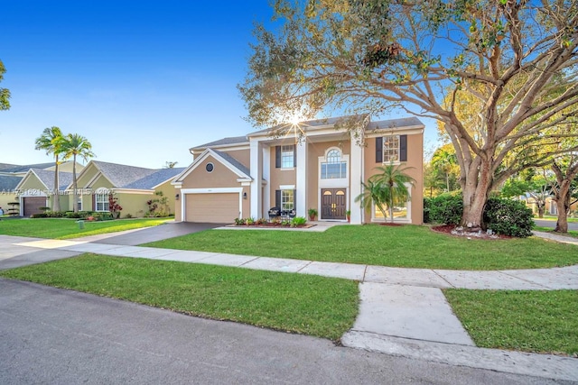 greek revival inspired property featuring a garage, aphalt driveway, a front lawn, and stucco siding