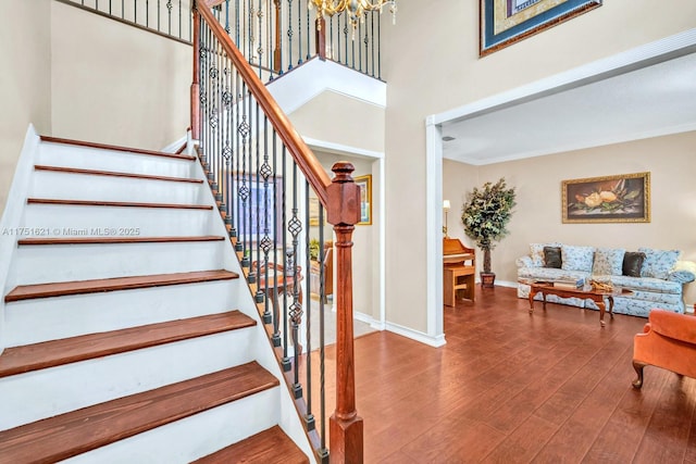 stairs with a high ceiling, baseboards, and wood finished floors