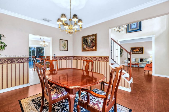 dining room featuring wood finished floors, visible vents, crown molding, and an inviting chandelier