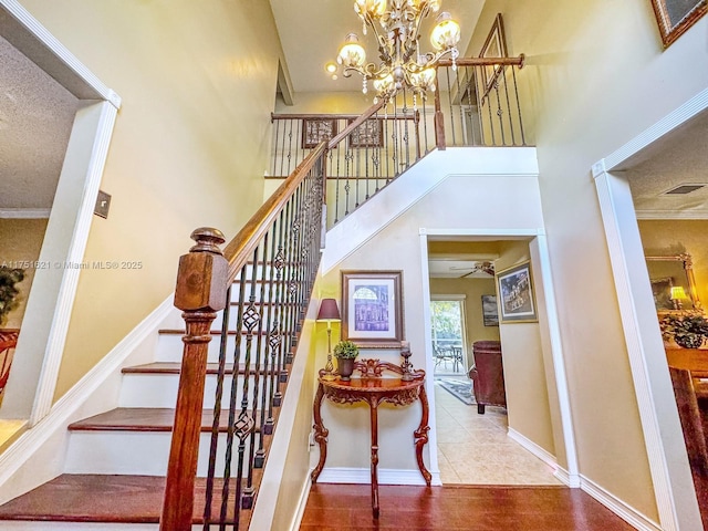 stairs featuring a high ceiling, visible vents, baseboards, tile patterned floors, and an inviting chandelier