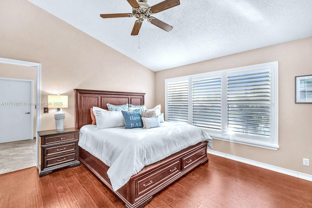 bedroom with vaulted ceiling, dark wood-style flooring, multiple windows, and a textured ceiling