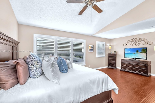 bedroom with a textured ceiling, wood finished floors, a ceiling fan, baseboards, and vaulted ceiling