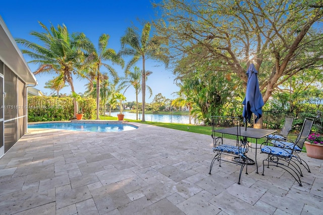 outdoor pool featuring outdoor dining space, a patio area, and a water view