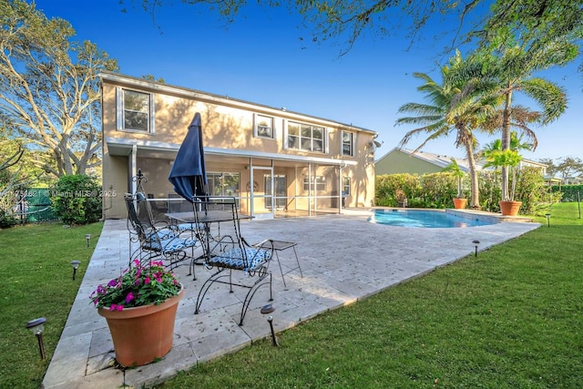 back of house with a yard, a patio, a sunroom, and stucco siding