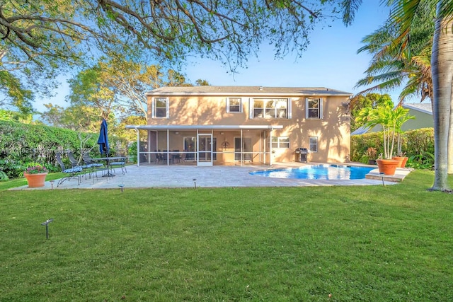 rear view of house with stucco siding, a lawn, a sunroom, a patio area, and an outdoor pool