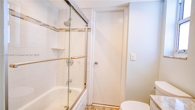 bathroom featuring toilet, shower / bath combination with glass door, and vanity