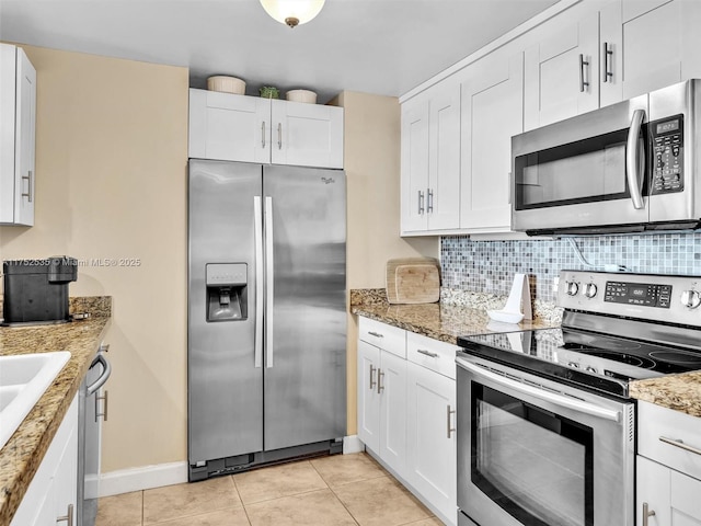 kitchen with white cabinets, light tile patterned floors, appliances with stainless steel finishes, and decorative backsplash