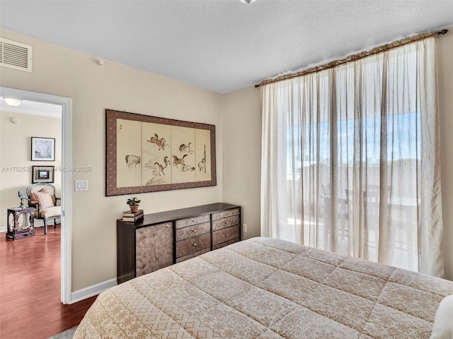 bedroom with baseboards, a textured ceiling, visible vents, and dark wood-type flooring